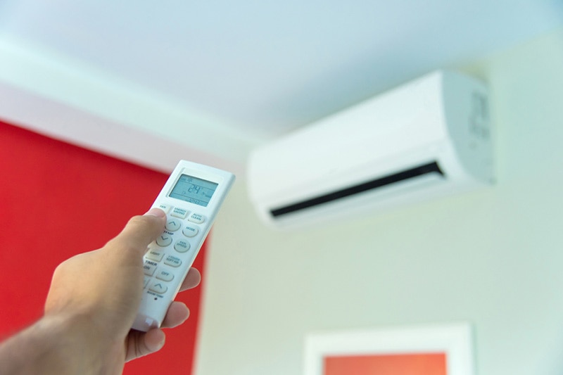 DUC_002 - 2 iStock-956818548 person holding a remote controlling a ductless system