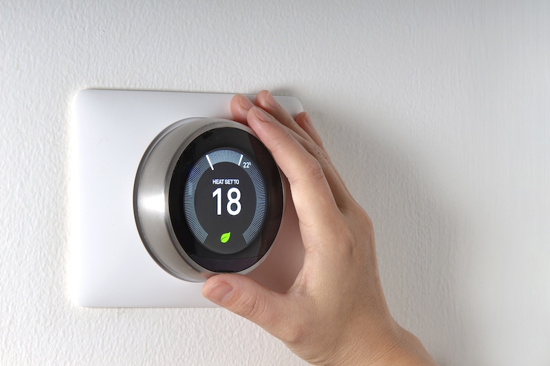 Smart Thermostat with a hand saving energy | Top 10 Ways to Reduce Your Energy Bill in 2022